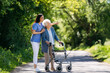 © Halfpoint - Female caregiver and senior woman with walker on walk in nature. Nurse and elderly woman enjoying a warm day in nursing home, public park.