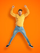 © New Africa - Positive young man jumping on orange background