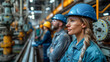 © Pavel Lysenko - A woman in a blue hard hat and safety glasses stands on a factory floor, gazing intently at the machinery while other workers stand behind her