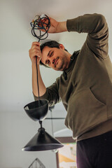 man himself repaired lamp on the ceiling in the kitchen at home