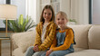 © Yuliia - Two happy Caucasian children little girls daughters looking at camera together dental healthy toothy smile sisters kids friends posing relax showing positive emotion family couch living room indoors