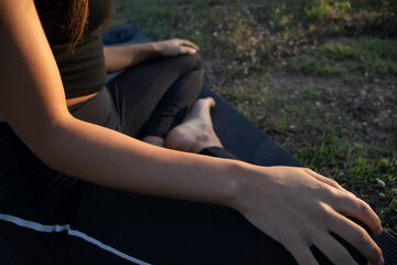 Beautiful young female practicing yoga in nature on a green grass during golden hour in summertime in the mountain village El Papiol, near Barcelona, Spain 