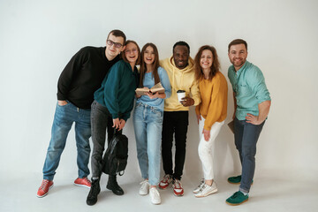 Wall Mural - Positive friends. Group of young people are standing against white background