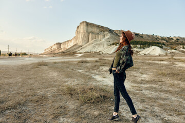 Wall Mural - Woman in jeans and hat standing confidently in front of majestic mountain range