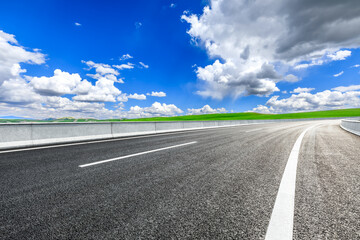 Asphalt highway road and green meadow with mountain nature landscape under blue sky