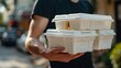 © ifoto - Close up of a man's hand holding a white polystyrene take-out food box with two stacked on top