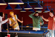 © LIGHTFIELD STUDIOS - Friends are gathered around a pool table, laughing and enjoying a casual game of billiards.