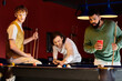 © LIGHTFIELD STUDIOS - Friends play a friendly game of billiards in a dimly lit room.