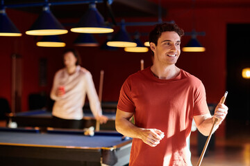 Wall Mural - Friends enjoy a game of billiards in a dimly lit bar.