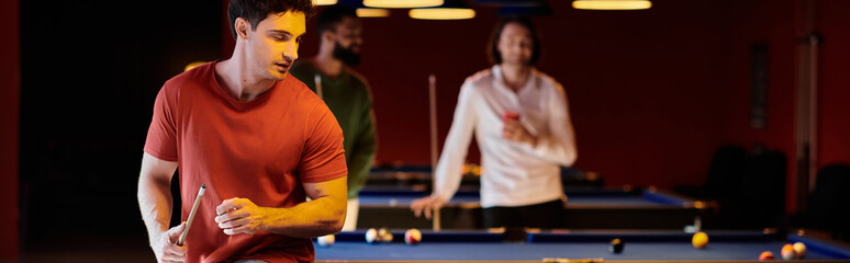 Friends gather around a pool table for a casual game of billiards, laughing and enjoying each others company.