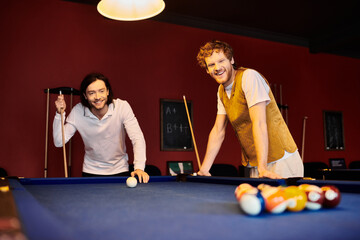 Wall Mural - Two men in casual clothing play pool together in a dimly lit room.