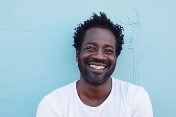 Wall Mural - Portrait of a satisfied afro-american man in his 30s smiling at the camera isolated on pastel blue background