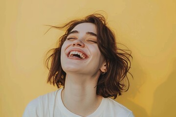 Wall Mural - Portrait of a content caucasian woman in her 20s laughing over pastel yellow background