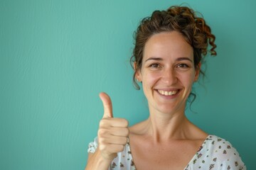Wall Mural - Portrait of a happy caucasian woman in her 40s showing a thumb up isolated on pastel green background