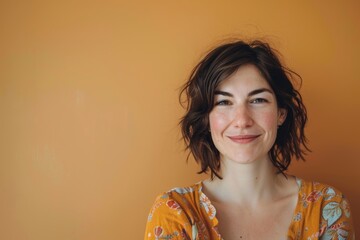 Wall Mural - Portrait of a satisfied woman in her 30s smiling at the camera isolated on pastel orange background