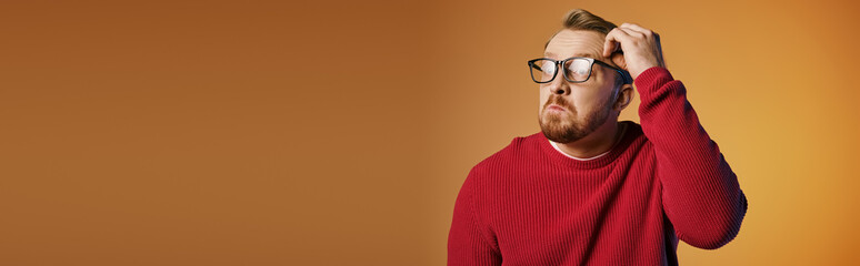 Wall Mural - A man in a red sweater holds his head in deep thought.