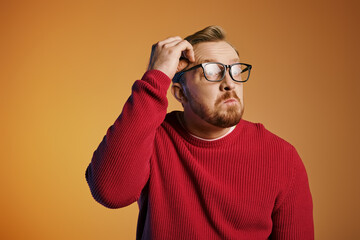 Wall Mural - A stylish man in a red sweater and glasses strikes a confident pose.