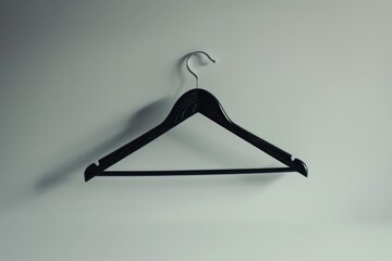 Wall Mural - A single black coat hanger mounted on a white wall, great for minimalist decor or fashion photography