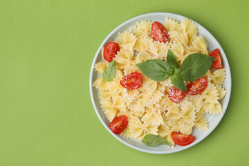 Tasty pasta with tomato, cheese and basil on green table, top view. Space for text