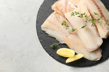 Wall Mural - Pieces of raw cod fish and lemon on light grey table, top view. Space for text