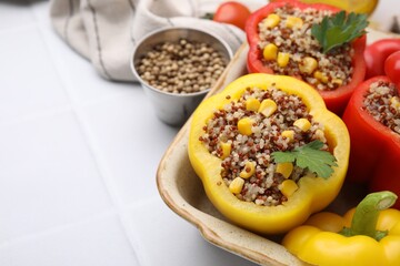 Wall Mural - Quinoa stuffed bell peppers and parsley in baking dish on white tiled table, closeup. Space for text