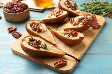 Wall Mural - Delicious baked pears with nuts, blue cheese, thyme and honey on light blue wooden table, closeup