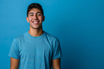 a Hispanic man in a blue sports jersey, expressing contentment with a relaxed smile on a blue studio background