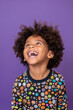 © wolfhound911 - an African American child feeling amused on a purple studio background