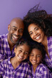 © wolfhound911 - an African American family in matching purple pajamas, smiling together on a purple studio background