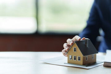 Wall Mural - Close up real estate agent holding small house model, Home loan.