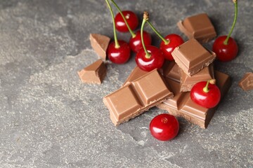 Poster - Fresh cherries with pieces of milk chocolate on grey textured table, space for text