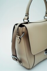 Wall Mural - A beige purse with a metal handle sitting on a white surface, perfect for use in product photography or as a prop in still life compositions