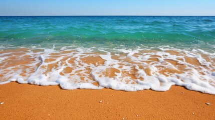 Wall Mural -  A sandy beach with waves approaching shore and a clear blue sky behind