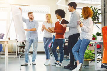 Aufkleber - A group of diverse individuals standing in a circle around a white board, engaged in discussion and collaboration. They are pointing, writing, and brainstorming ideas together in a meeting