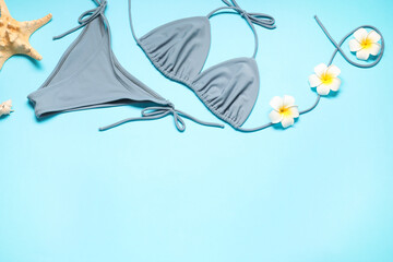Wall Mural - Flat lay composition with beautiful swimsuit, flowers and starfish on light blue background. Space for text