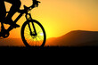 © STOCK PHOTO 4 U - Silhouette of a Cyclist Riding a Mountain Bike at Sunset with Scenic Mountain Background