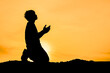 © STOCK PHOTO 4 U - Silhouette of a Person Praying at Sunset with a Golden Sky Background