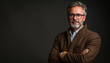© gearstd - Sophisticated mature man with glasses and a brown coat posing confidently against a dark background