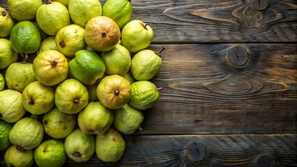 collection of green guavas arranged on a dark wooden surface. The fruits vary in size and are densely packed, occupying most of the visible area