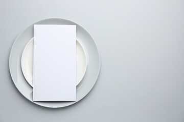 Wall Mural - Empty menu and plates on light grey background, top view. Mockup for design