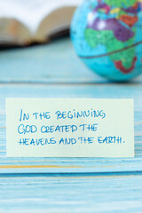 Wall Mural - In the beginning God created heavens and earth, handwritten quote with world globe and holy bible book in the background. Close-up. Christian biblical concept of creation.