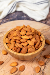 Wall Mural - Almonds on wood background. Roasted almonds in a bowl