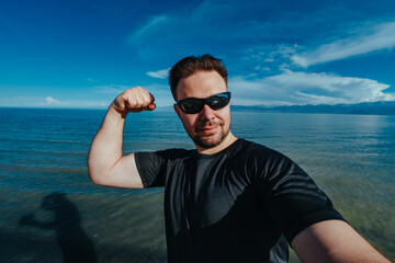 Wall Mural - Young man tourist self portrait on lake background on summer day