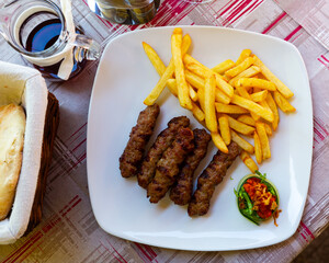 Wall Mural - Traditional dish of Balkan region Cevapcici, grilled sausages made of minced meat served with french fries and sauce