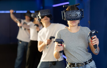 Female teenager in virtual reality headset with joystick in hands play network survival game in stone jungle of future. concept of altered reality.Immersive Technologies XR VR AR MR