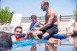 © Viga - Relatives of different ages are enjoying themselves in the swimming pool, having a great time together and supporting each other to make the most of their vacation