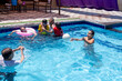 © Viga - Relatives of different ages are enjoying themselves in the swimming pool, having a great time together and supporting each other to make the most of their vacation
