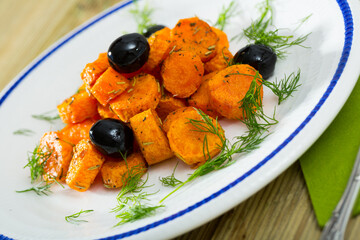 Wall Mural - Appetizing baked carrots in Provence style served with black olives and fresh chopped dill..