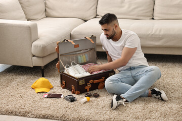 Canvas Print - Man packing suitcase on floor at home