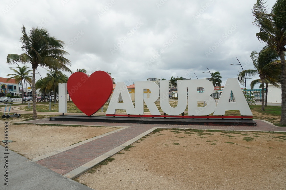 Oranjestad, Aruba, May 24, 2024: Big sign I love Aruba with red heart between letters exhibit near center of Oranjestad for tourist which are taking photo as memory. Thera are palm trees.  